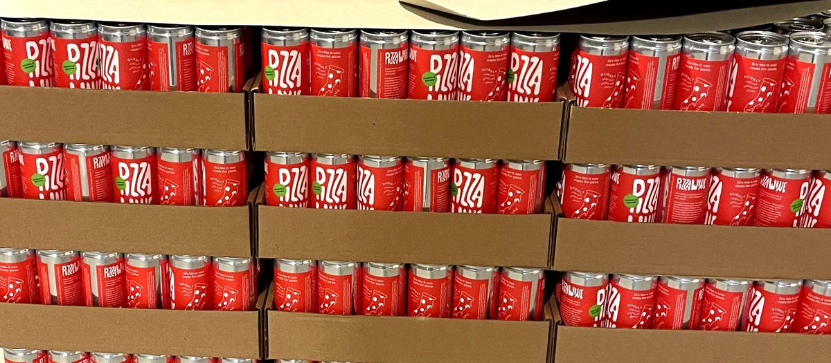 Trays of freshly canned Pizza Wine stacked on a pallet